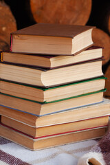 a close stack of old books on the woolen blanket  on wooden background in vintage style. Literature, education, hobby, reading and lifestyle