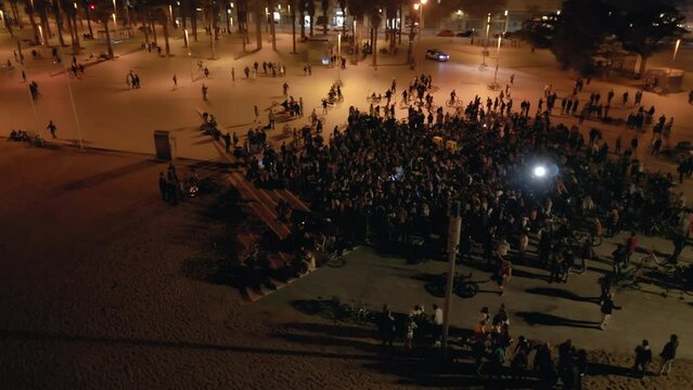 Aerial drone shot above crowd at open-air concert at night on the coast