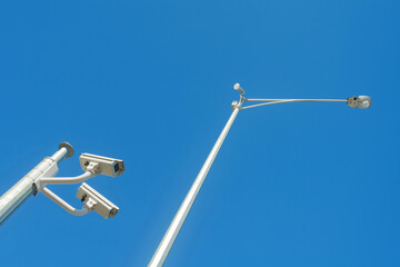 Two CCTV cameras and streetlight from a low angle
