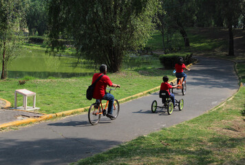 Familia de tres personas dando un paseo en bicicleta por el parque. 