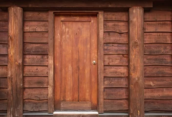 Foto op Plexiglas Oude deur Houten voordeur naar rustieke hut. Houten muur met oude deur. Rustieke blokhut met voordeur in het bos BC.
