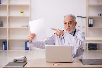 Old male doctor working in the clinic