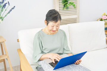 家でパソコンを使う高齢者女性