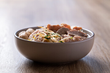 Rice noodles soup with pork in bowl on wooden background, Asian food