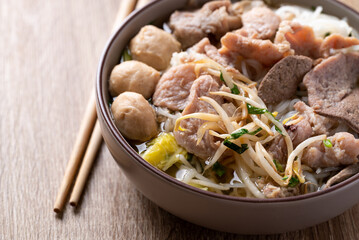 Rice noodles soup with pork in bowl on wooden background, Asian food