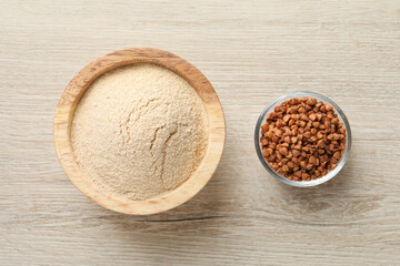 Buckwheat flour and grains in bowls on white wooden table, top view