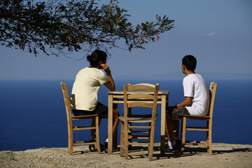 Siblings sitting at a café and watching the Aegean Sea in Gokceada. 