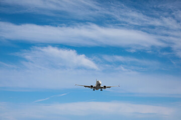 Fototapeta na wymiar Modern white airplane flying in cloudy sky