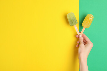Woman holding delicious ice pops on color background, top view with space for text. Fruit popsicle