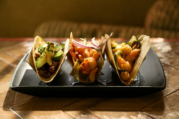 Delicious tacos with shrimps and vegetables on table
