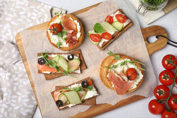 Tasty rusks and rye crispbreads with different toppings on light grey table, flat lay