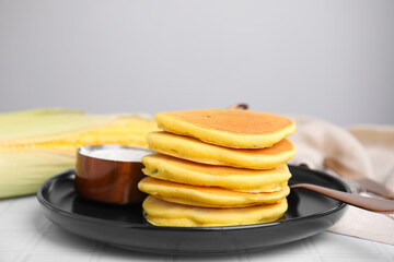 Tasty corn pancakes served on tiled table, closeup