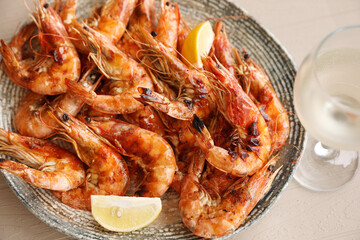 Plate of delicious cooked shrimps served with lemon and wine at table, closeup