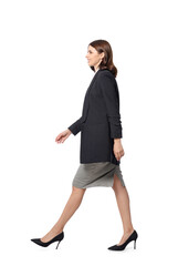 Fototapeta premium Beautiful young woman in formal suit walking on white background