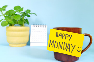 Welcome, hello and happy Monday concept. Selective focus of coffee cup with bright yellow paper note and written message.