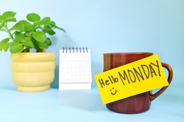 Welcome, hello and happy Monday concept. Selective focus of coffee cup with bright yellow paper note and written message.