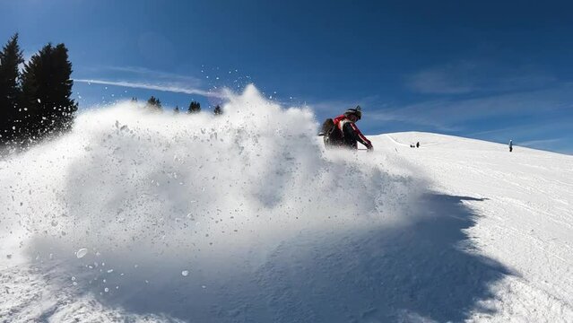 Caucasian man spray fresh snow powder at camera on ski slope, slow motion