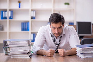 Fototapeta na wymiar Young male employee unhappy with excessive work at workplace