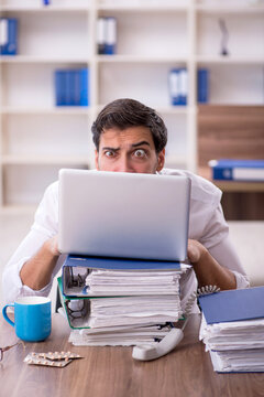 Young male employee unhappy with excessive work at workplace