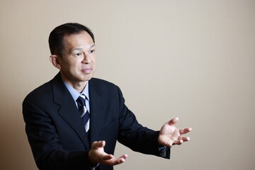 Middle-aged Japanese male businessman wearing navy blue suit on white background. Conceptual image of a project proposal, strategic business success and negotiation closing.