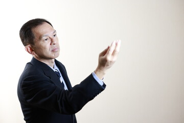 Middle-aged Japanese male businessman wearing navy blue suit on white background. Conceptual image of a project proposal, strategic business success and negotiation closing.