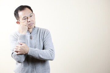 Middle-aged Japanese man in gray turtleneck wool sweater under white background. Concept image of Warm Biz, stability in daily life, and sustainable living.