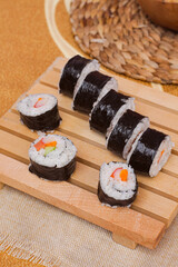 Top view a set of fresh and cheap japanese sushi rolls with crabstick, cucumber, carrot and sausage served on a wooden board