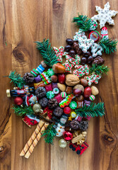 Festive confections and ornaments in the shape of a tree on a wooden board.