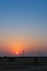 Dawn light in desert sky with Electrical power generating wind mills producing alterative eco...
