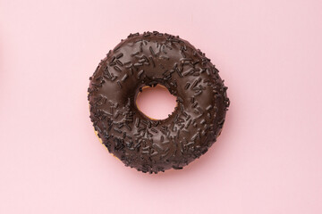 Dark chocolate donut on a pink background. The minimal concept of popular baking.