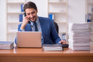 Fototapeta premium Young businessman employee and too much work in the office