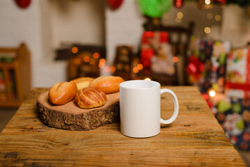 White cup on wooden table. Mug and breads on table with christmas background.