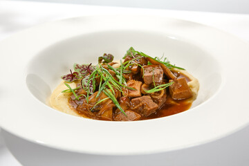 Elegant stew beef with mashed potatoes in  restaurant. Beef bourguignon on light background with shadows of leaves Braised black angus meat with potato cream in summer menu