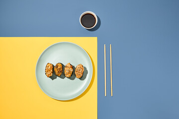 Gunkan sushi set in plate on coloured background with chopsticks and soy sauce. Minimal composition...
