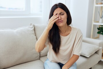 Obraz premium Woman sitting on sofa at home pain in nose and throat, cold and allergy, covid-19 disease, temperature