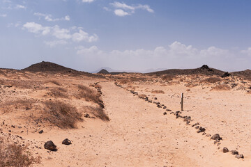 Road across dry desert defined by rocks, Lobos Island, Spain