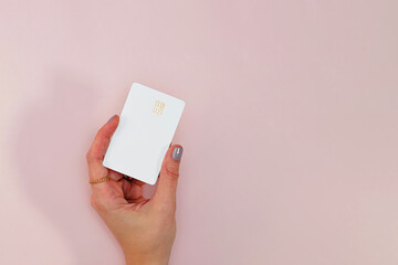 Woman's hand holding white plastic credit or debit card with chip