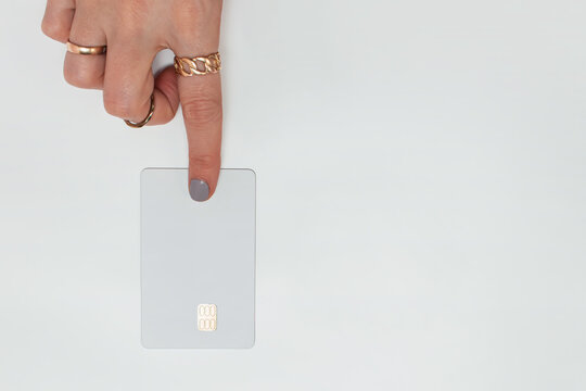 Women's index finger pushes white credit card , top view