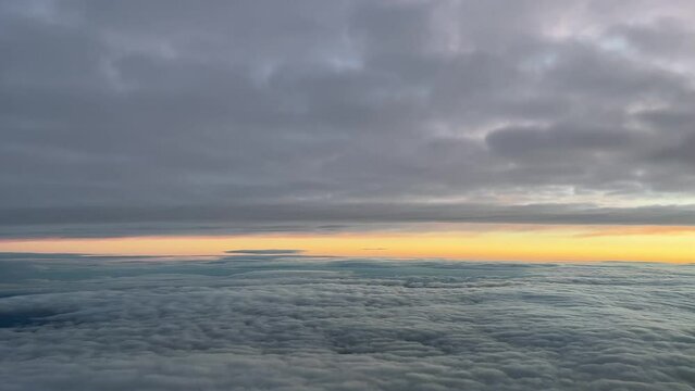 Pilot view from a jet cockpit while flying between layers of clouds at dawn with an orange sky, at 10000m high in a cold winter moorning.