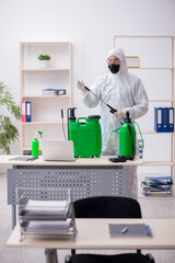 Young male contractor disinfecting office during pandemic