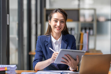 Fototapeta na wymiar Brown haired wearing light blue jacket smiling Asian woman work with document laptop in office, doing planning analyzing the financial report, business plan investment, finance analysis concept.