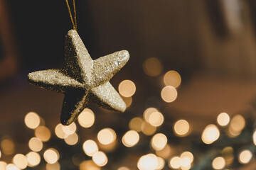 Luces de navidad en desenfoque y primer plano de una mano sosteniendo estrella dorada. Concepto de...