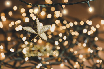 Luces de navidad en desenfoque y primer plano de una mano sosteniendo estrella dorada. Concepto de...