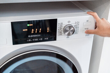 close up of hand pushing start button of washing machine.