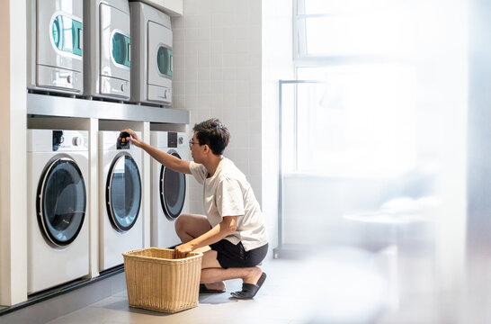 Asian Young Man Is Doing Laundry In The Public Laundry Room.