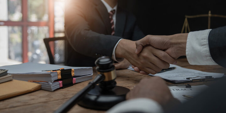 Businessman shaking hands to seal a deal with his partner lawyers or attorneys discussing a contract agreement.