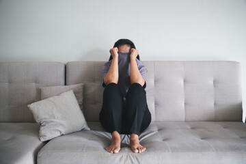 Schizophrenia with lonely and sad in mental health depression concept. Depressed woman sitting against on the sofa at home with dark room feeling miserable. Women are depressed, fearful and unhappy.