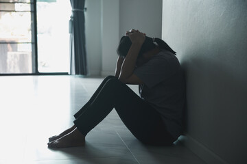 Schizophrenia with lonely and sad in mental health depression concept. Depressed woman sitting against wall at home with a shadow on wall feeling miserable. Women are depressed, fearful and unhappy.