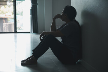 Schizophrenia with lonely and sad in mental health depression concept. Depressed woman sitting against wall at home with a shadow on wall feeling miserable. Women are depressed, fearful and unhappy. - obrazy, fototapety, plakaty