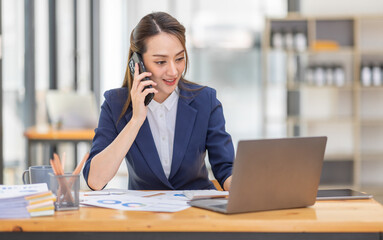 Shot of a asian young business Female working on laptop computer in her workstation.Portrait of Business people employee freelance online marketing Call phone e-commerce telemarketing concept.